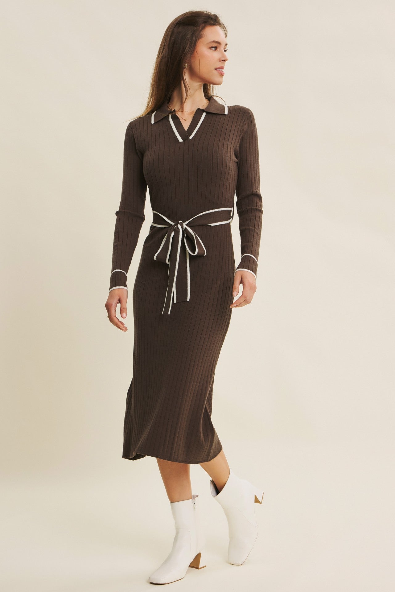 woman wearing a brown ribbed midi dress with a white collar and tie waist, paired with white ankle boots