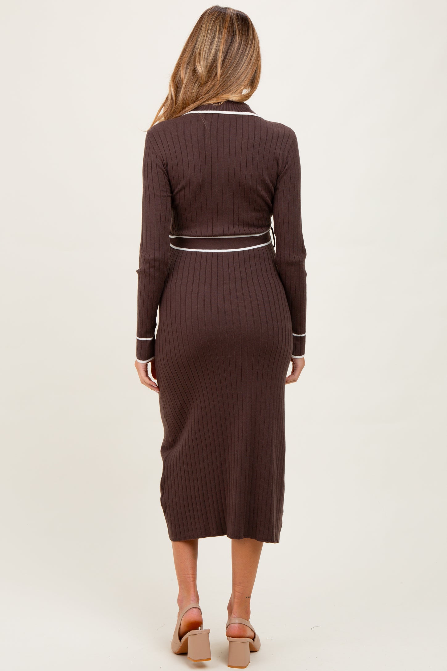 woman wearing a brown ribbed maternity dress with a fitted silhouette and long sleeves, showing a pregnant belly