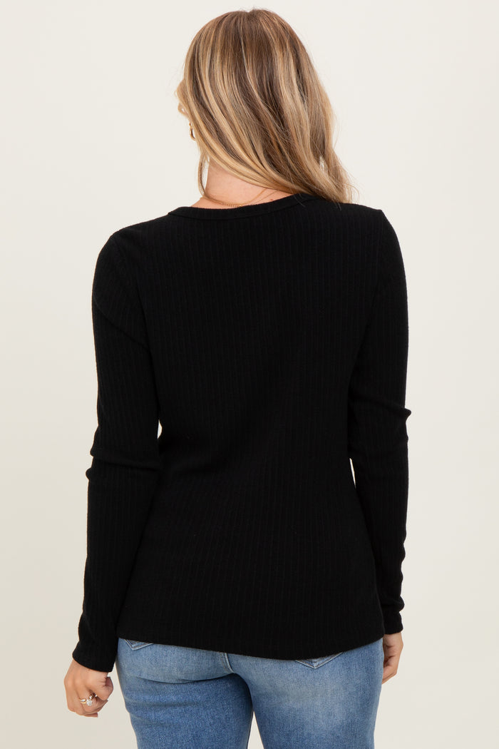 woman wearing a black ribbed long sleeve top, viewed from the back with light blue jeans