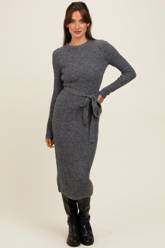 woman wearing a dark gray ribbed knit long sleeve dress with a waist tie and black knee-high boots