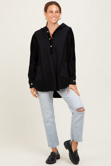 woman wearing a black hooded oversized sweater with buttons and pockets, paired with light blue ripped jeans and black shoes