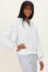 woman wearing a white floral print pullover sweatshirt with a quarter zip and relaxed fit