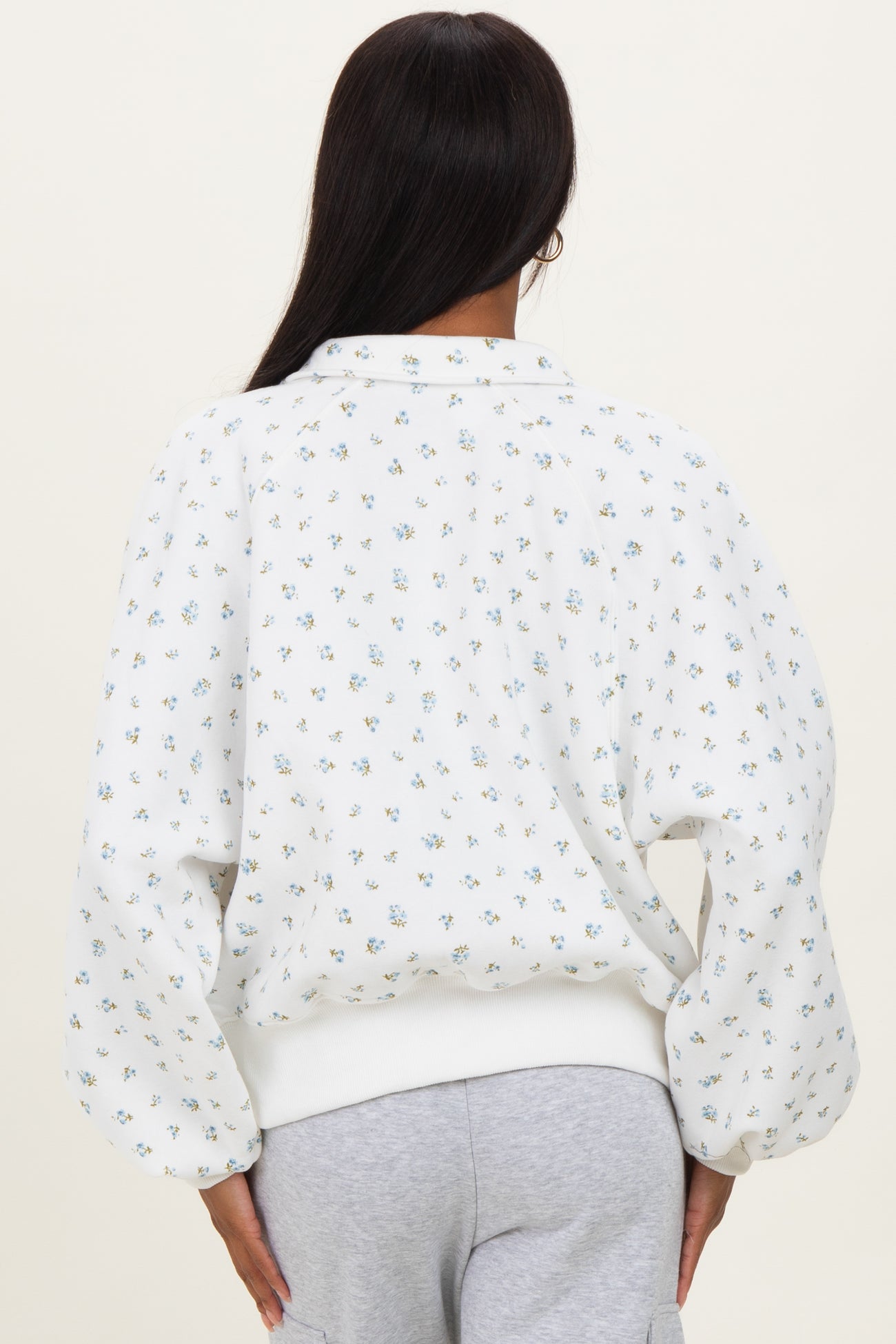woman wearing a white floral patterned sweatshirt with balloon sleeves, seen from the back