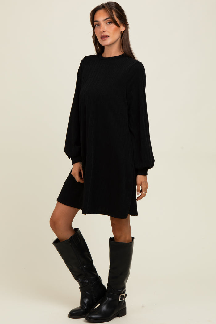 woman wearing a black long sleeve dress with puffed sleeves and knee-high black boots