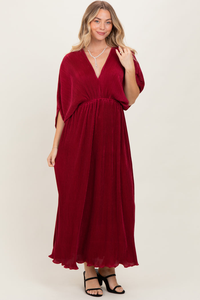 woman wearing a deep red maxi dress with a v-neckline and flowy sleeves, styled with black block heels