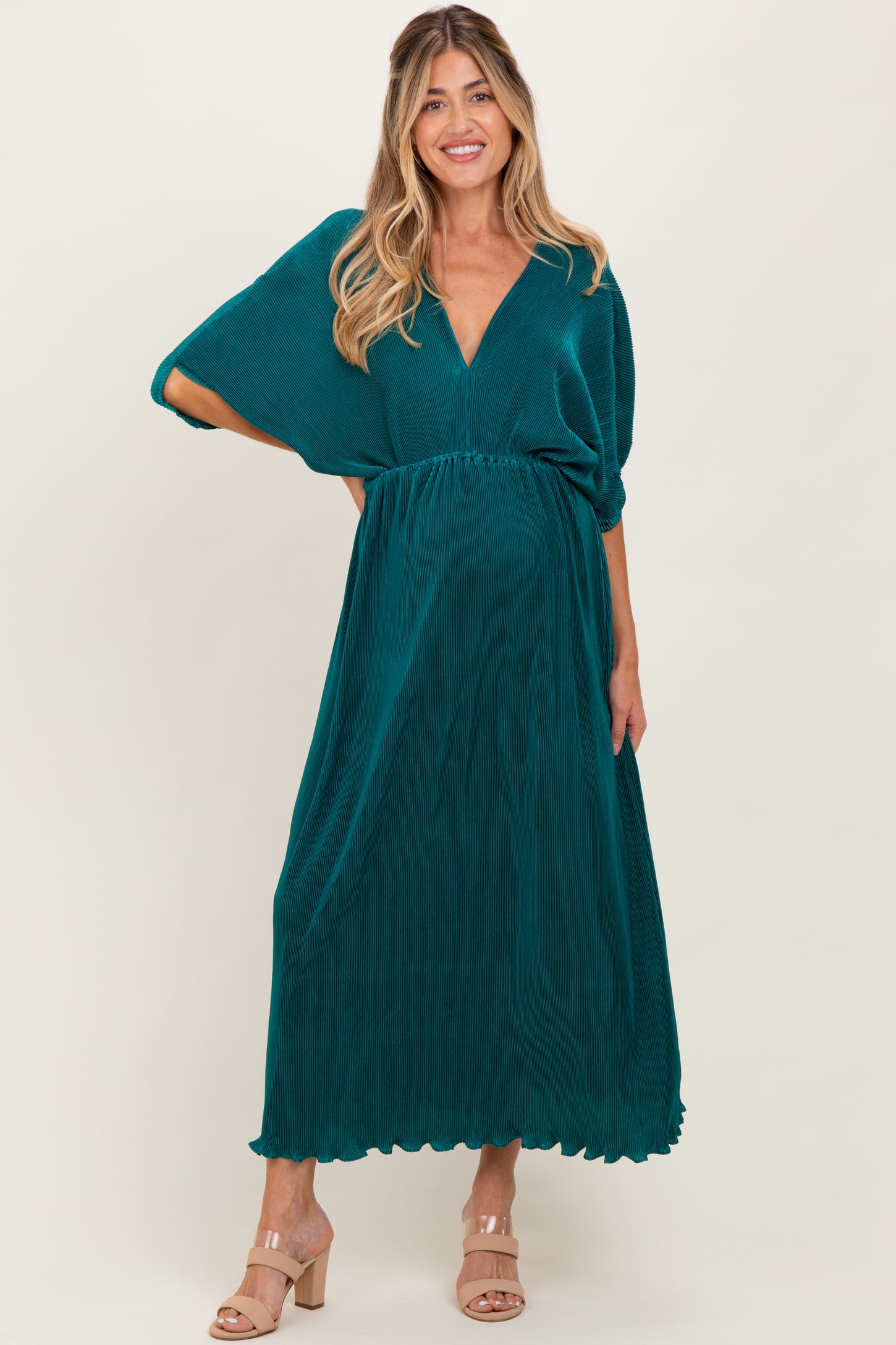 woman wearing a teal maternity maxi dress with a v-neck and flowy sleeves, showcasing her baby bump