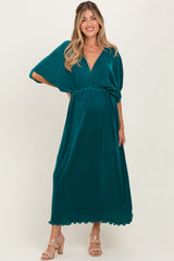 woman wearing a teal maternity maxi dress with a v-neck and flowy sleeves, showcasing her baby bump
