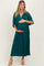 woman wearing a teal maternity maxi dress with short sleeves, gently cradling her baby bump