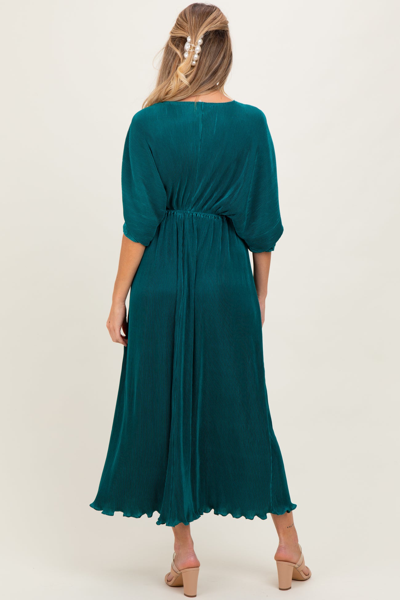 woman wearing a teal maternity dress with half sleeves and an elastic waist, showing a flowing silhouette from the back