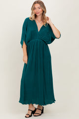 woman wearing a teal maxi dress with a v-neck and short dolman sleeves, standing against a neutral background