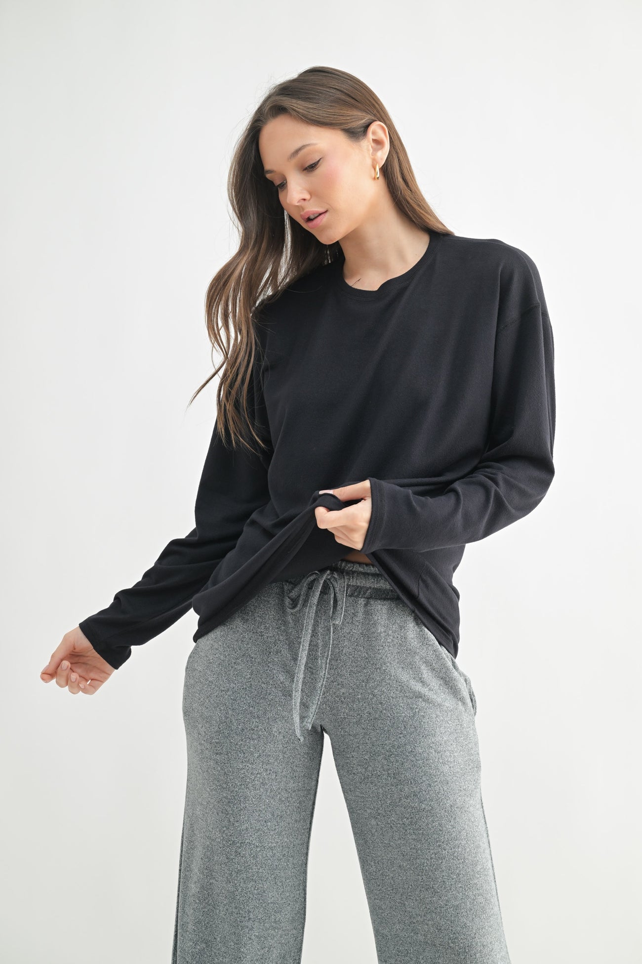 woman wearing a black long sleeve shirt and gray sweatpants with a relaxed fit