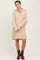 woman wearing a beige oversized knitted dress with a collar and long sleeves, paired with brown ankle boots