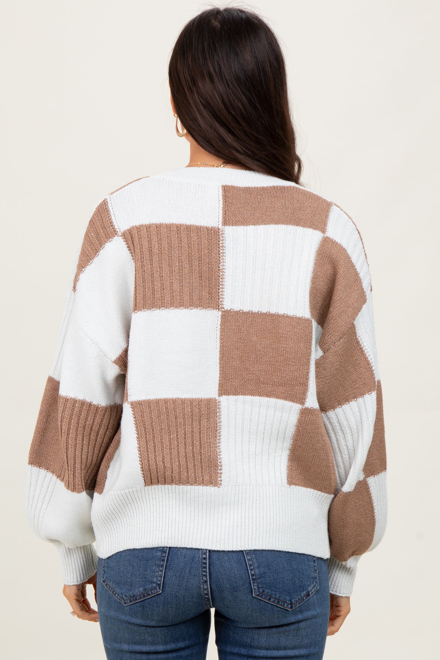 woman wearing a cream and brown checkered sweater with a relaxed fit and balloon sleeves, viewed from the back