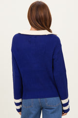 woman wearing a back view of a blue ribbed sweater with a white collar and striped cuffs