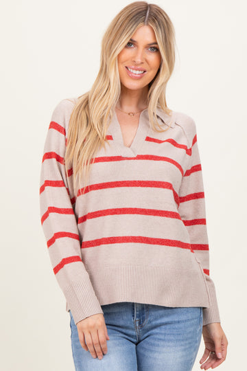 woman wearing a beige striped sweater with red stripes and a v-neckline, paired with blue jeans