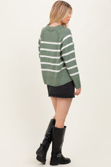 woman wearing a green striped sweater with white stripes and a black denim skirt, paired with knee-high black boots