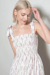 woman wearing a white floral smocked sundress with tie straps and a fitted bodice