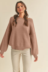 woman wearing a blush oversized ribbed sweater with balloon sleeves paired with white corduroy pants