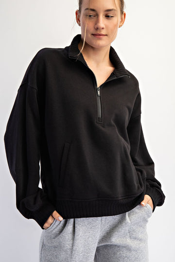woman wearing a black quarter-zip pullover sweatshirt with a relaxed fit and side pocket, paired with gray sweatpants