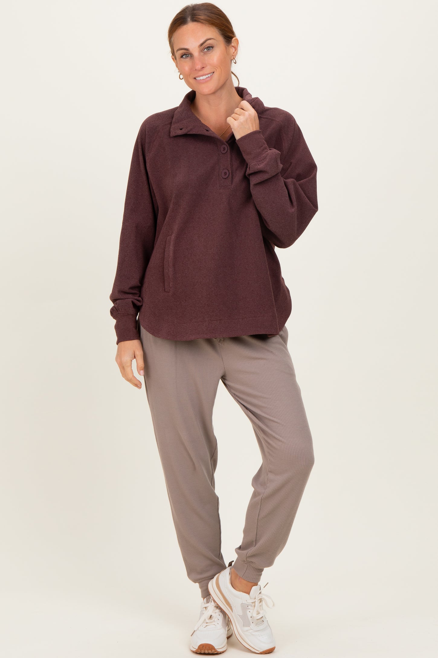 woman wearing a maroon fleece pullover with a collar and buttons, paired with gray jogger pants and white sneakers