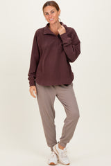 woman wearing a maroon fleece pullover with a collar and buttons, paired with gray jogger pants and white sneakers