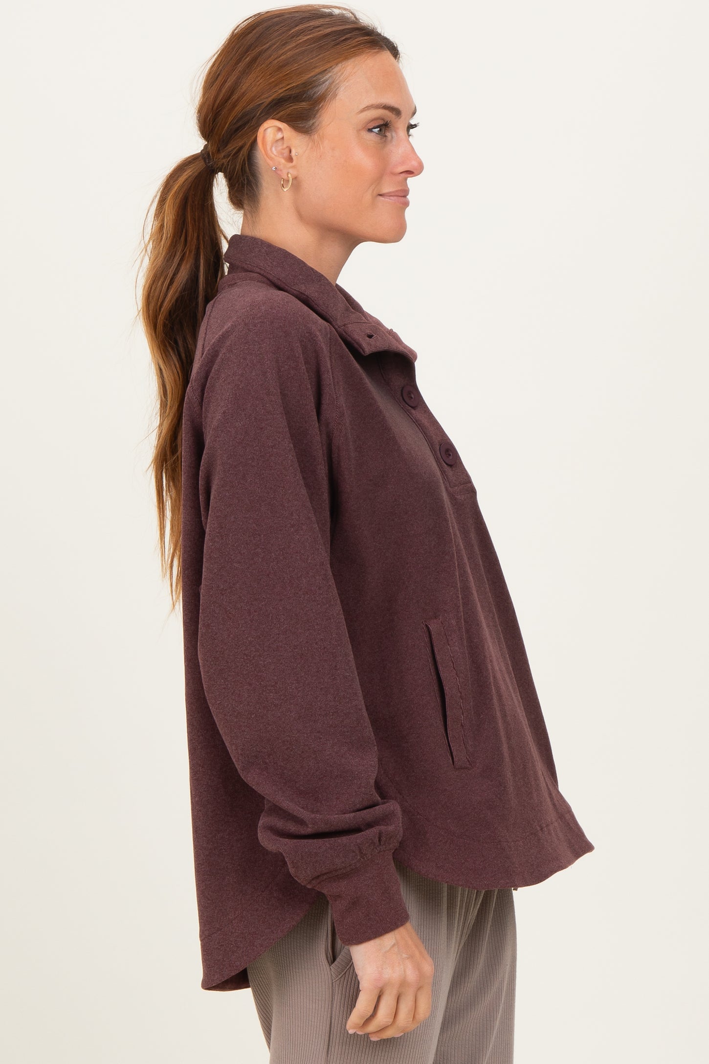 woman wearing a burgundy oversized button-up shirt jacket with a relaxed fit and side pockets