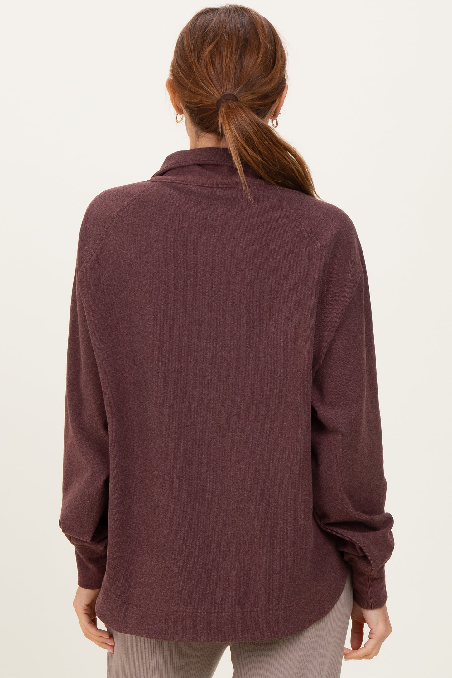 woman wearing a burgundy long sleeve pullover top with a relaxed fit, seen from the back