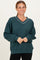 woman wearing a dark green oversized sweatshirt with a v-neck and white trim details