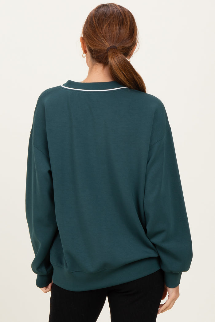 woman wearing a dark teal oversized sweatshirt with white collar detailing, viewed from the back