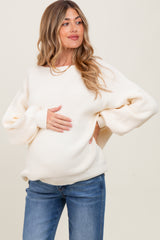 woman wearing a cream long sleeve maternity sweater with balloon sleeves and a visible baby bump