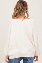 woman wearing a cream oversized maternity sweater with a relaxed fit and wide sleeves, view from the back