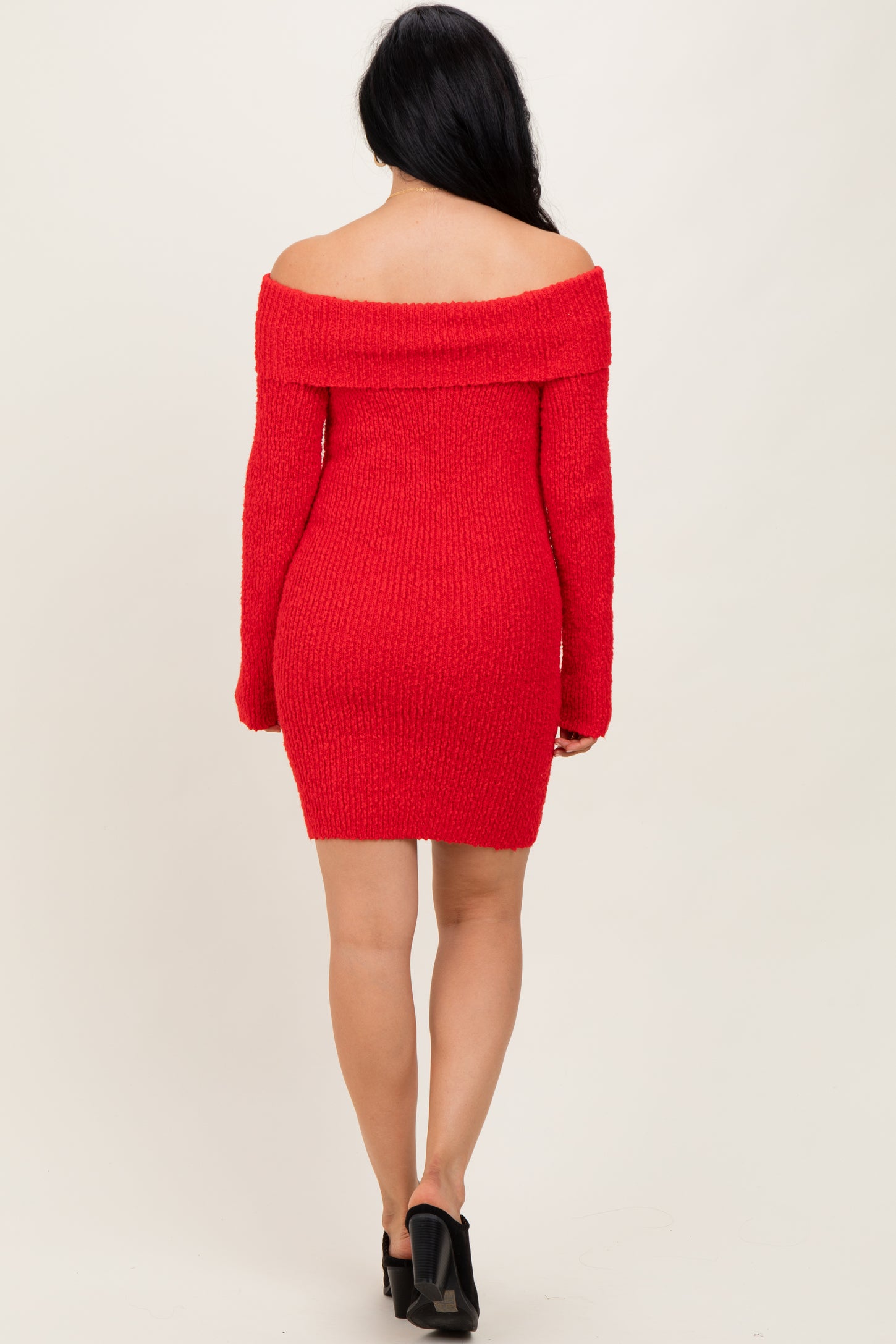 woman wearing a red off-shoulder sweater dress with long sleeves and a fitted silhouette