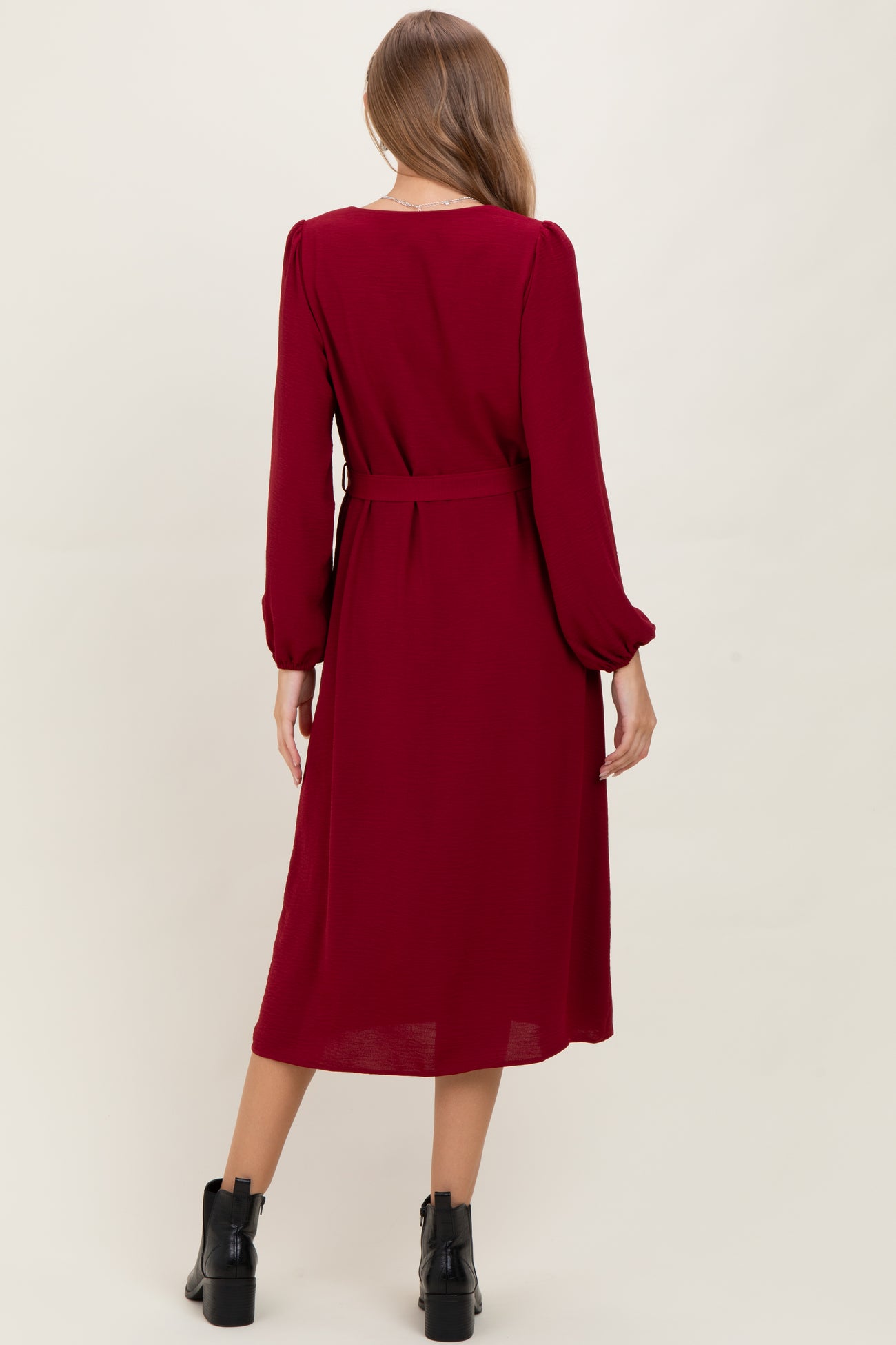 woman wearing a burgundy long sleeve maternity dress with a belt, view from the back