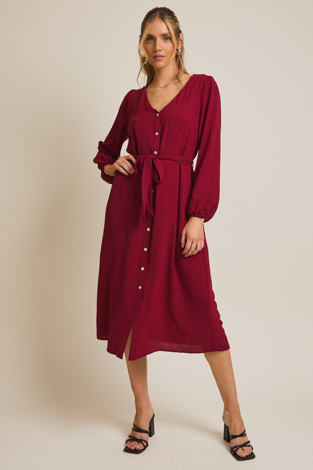 woman wearing a burgundy button-up midi dress with long sleeves and a tied waist detail