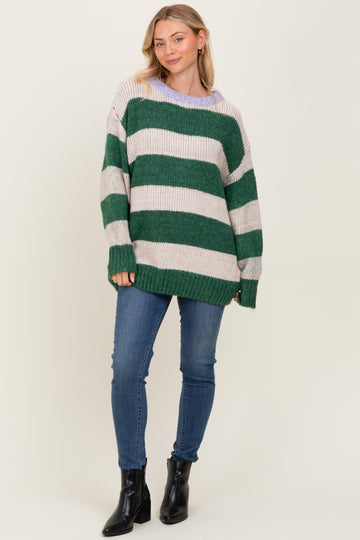 woman wearing a green and cream striped oversized knit sweater with a relaxed fit and blue skinny jeans
