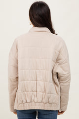woman wearing a cream quilted jacket with an elasticized hem, showing the back view