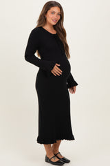 woman wearing a black ribbed maternity dress with ruffle sleeves and hem, highlighting her baby bump