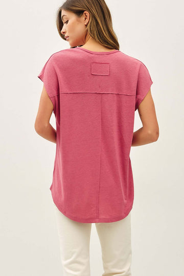 woman wearing a pink short sleeve top with a relaxed fit and a patch detail on the back