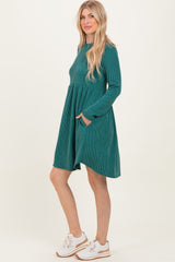woman wearing a teal ribbed long sleeve a-line dress with pockets and white sneakers