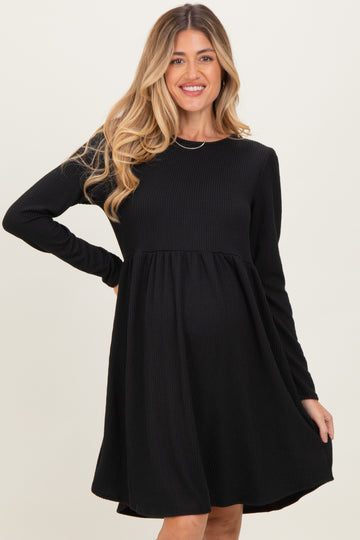 woman wearing a black long sleeve maternity dress with a fitted bodice and flared skirt, showcasing her baby bump