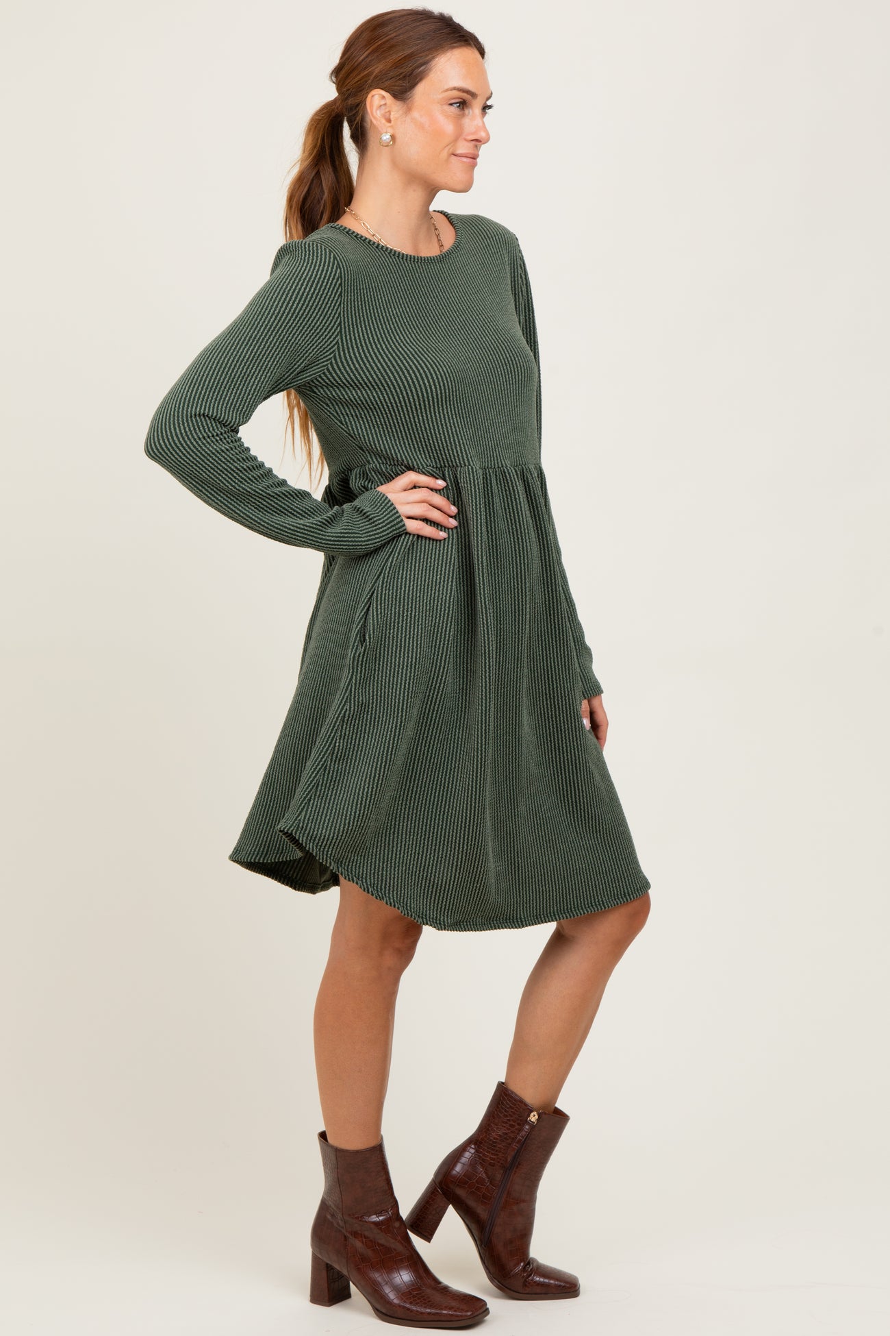 woman wearing a green ribbed long sleeve dress with a flared skirt and brown ankle boots