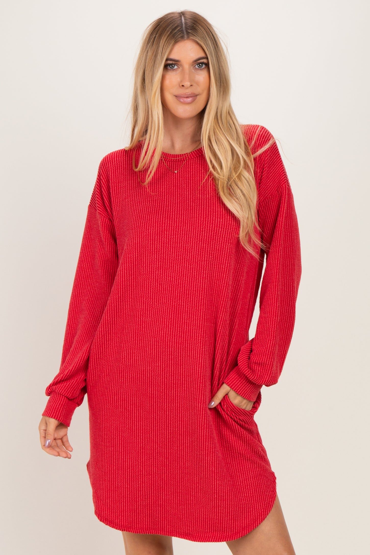 woman wearing a red ribbed long sleeve dress with a relaxed fit and side pockets