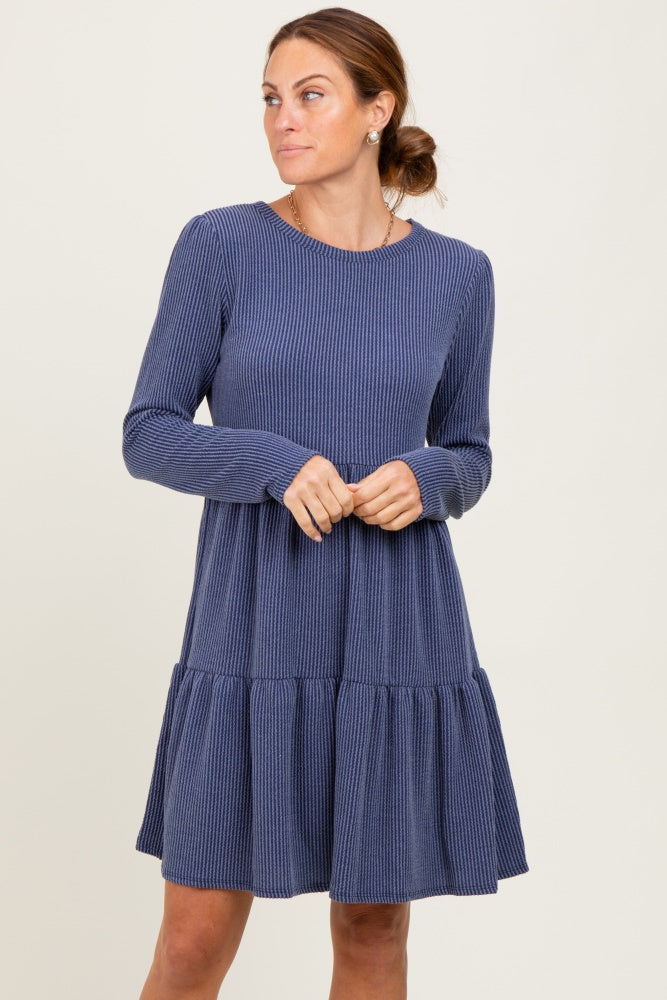 woman wearing a navy ribbed long sleeve dress with a tiered ruffle hem