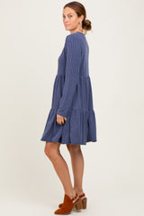 woman wearing a navy blue striped long sleeve tiered dress with a relaxed fit and side view pose