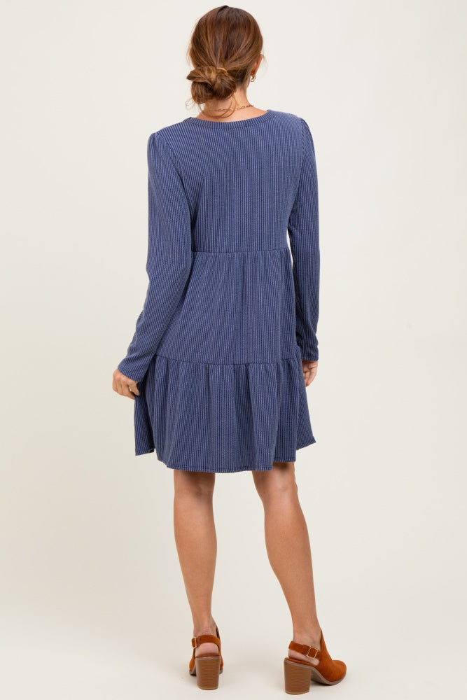 woman wearing a navy blue long sleeve tiered dress with a ribbed texture, viewed from the back