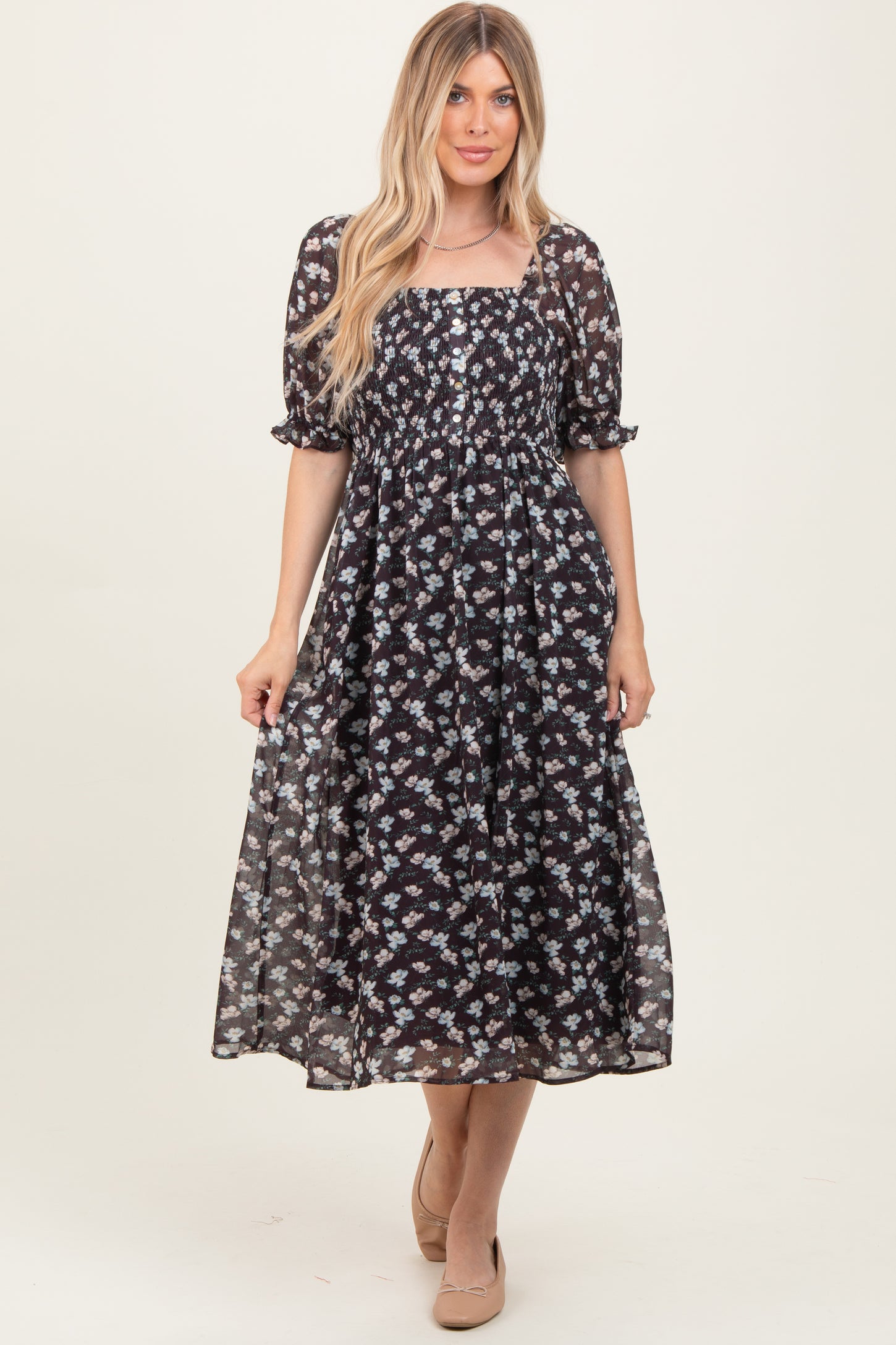 woman wearing a black floral midi dress with short puff sleeves and a smocked bodice