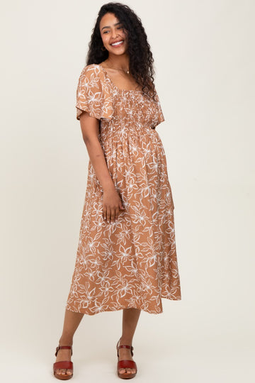 woman wearing a brown floral print maternity dress with short sleeves and a smocked bodice, showing her baby bump