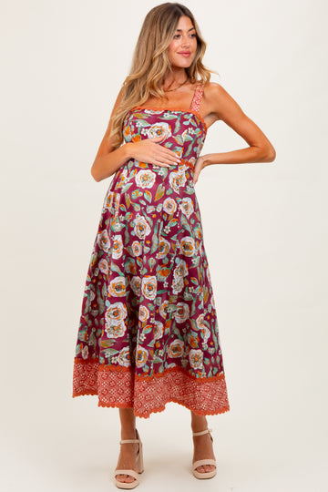 woman wearing a floral maternity maxi dress with a fitted bodice and a flared skirt, showcasing her baby bump