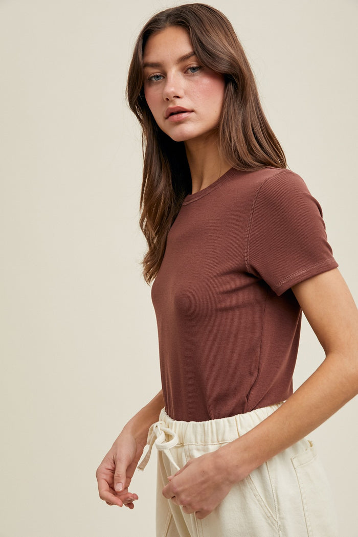 woman wearing a fitted brown short sleeve t-shirt paired with cream colored drawstring pants