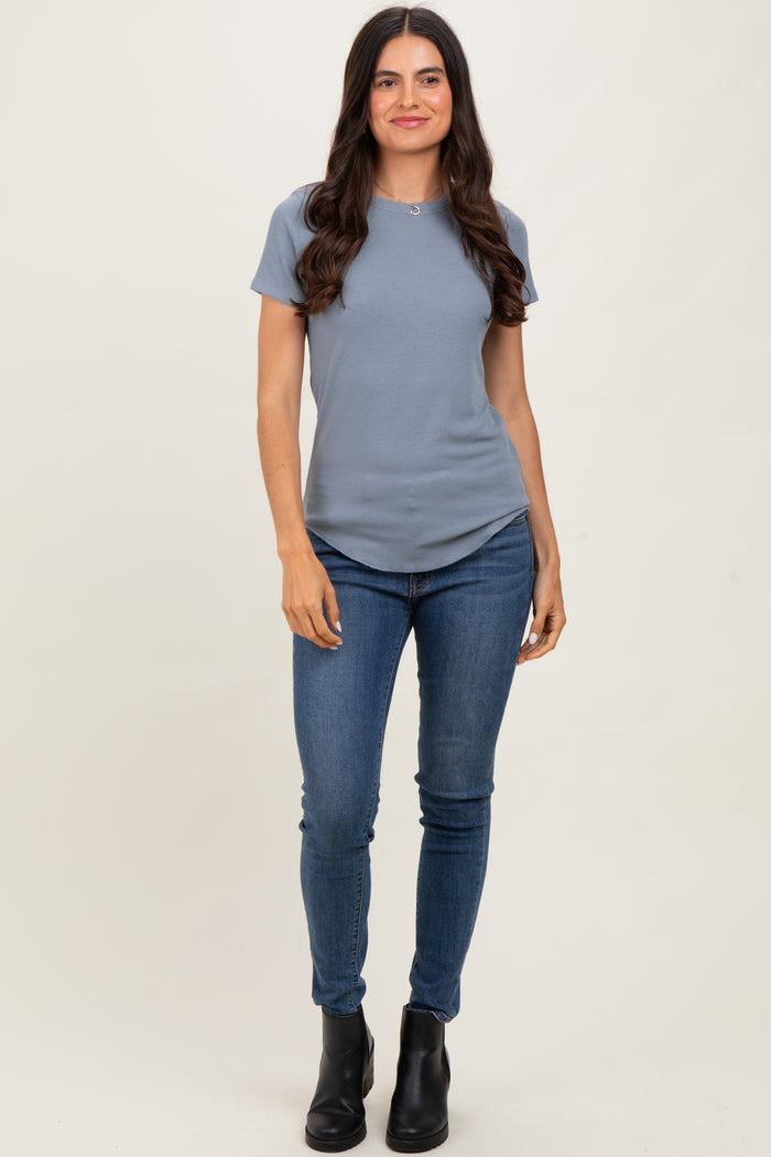 woman wearing a light blue short sleeve top and dark skinny jeans, paired with black ankle boots